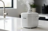 Compact white Toshiba 3-Cup Mini Rice Cooker on kitchen counter with steam rising
