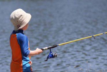 Child holding an affordable beginner fishing pole by a lake