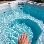 Person testing spa water with digital test kit beside hot tub