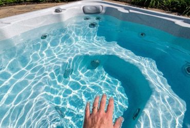 Person testing spa water with digital test kit beside hot tub