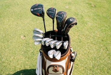 Golf clubs neatly arranged in individual dividers of a 14-way cart bag.