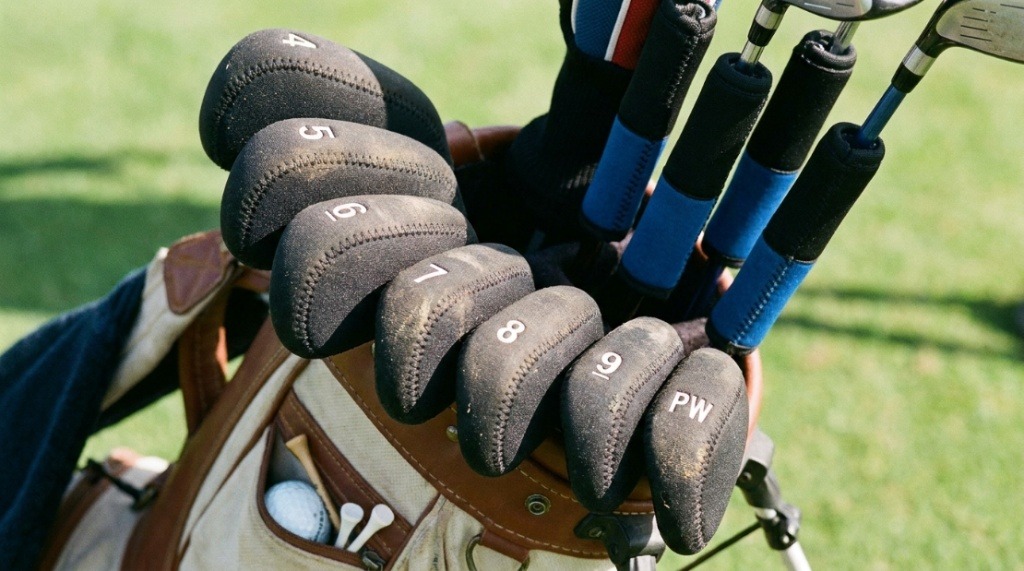 Protective neoprene covers wrapped tightly around golf iron heads.